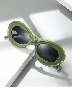 Detail view of olive green oval cat-eye sunglasses with dark lenses on geometric blocks