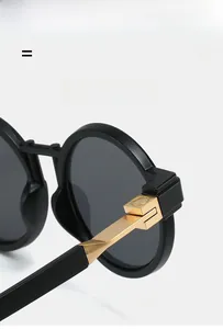 Detail of round sunglasses featuring black frames and flexible gold metal temples