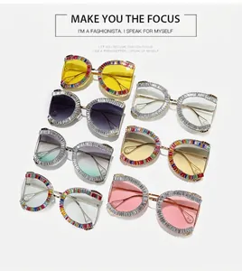 Detail view of colorful oversized sunglasses featuring rhinestone frames and pearl tips