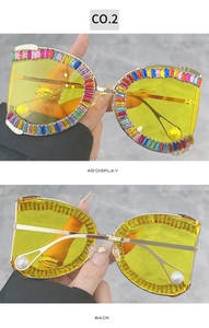 Detail view of oversized yellow sunglasses with rhinestone edges and pearl temple tips