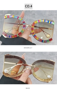 Detail of oversized sunglasses featuring rainbow rhinestones and pearl temple accents