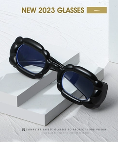Detail of chunky black rectangular frame glasses with blue lenses on a white stone pedestal