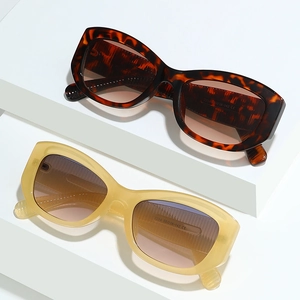Lunettes de soleil œil-de-chat en écaille et jaune sur supports blancs géométriques
