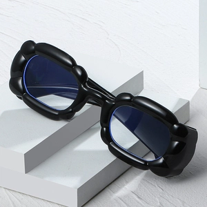 Chunky black puff frame glasses with blue transparent lenses on a white stone base
