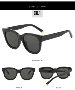 Macro view of oval sunglasses featuring black wide frames and golden temple accents