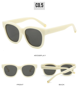 Detail view of oval cream sunglasses featuring dark grey lenses and gold metal accents