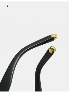 Detail of curved black sunglasses legs with gold rose engraving and metallic finish