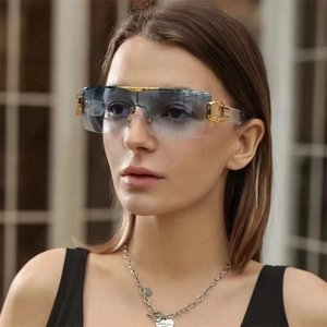 Detail of gradient blue rimless sunglasses with golden C-shaped metal hinge accents