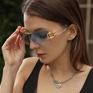 Detail of oversized rimless sunglasses with gradient blue lenses and gold metal accents