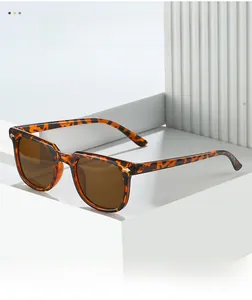 Detailed close-up of tortoise shell square sunglasses with metal hinge accents on a white stand