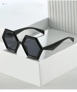Close-up of black geometric hexagonal sunglasses on a white minimalist display stand