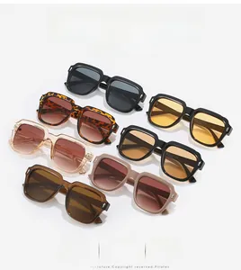 Flat lay of square sunglasses in seven assorted colors featuring thick frames and rivets