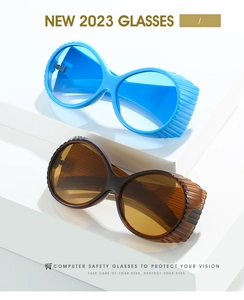 Detail of oversized retro oval sunglasses with side shields on white display stands