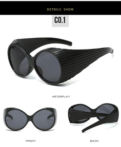 Detail view of oval oversized sunglasses with textured horizontal lines on black frame