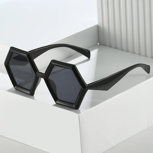 Chic black hexagonal oversized sunglasses with dark lenses on a minimalist display stand