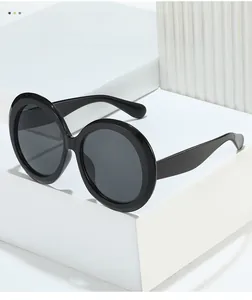 Close-up of oversized round sunglasses with glossy black frames on minimalist backdrop