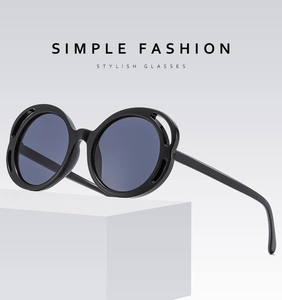 Detail of round oversized sunglasses with double-layer hollow frames and dark lenses