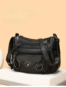 Detailed view of black pebbled PU leather crossbody bag with multiple silver zipper pockets