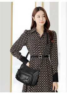 Detailed view of black multi-zip leather crossbody bag worn by a model in soft lighting
