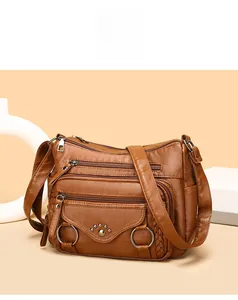 Detail view of brown multi-pocket crossbody bag with metallic rings and woven strap