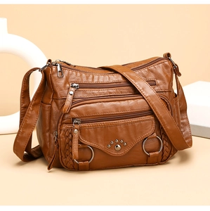 Detail of brown faux leather crossbody bag with multiple zippers and metal rivets