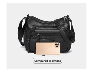 Macro detail of black leather crossbody bag with braided zippers shown next to an iPhone