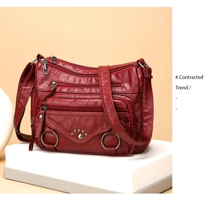 Detail view of burgundy soft leather bag with multi-zipper pockets and rivet claw patterns