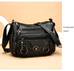 Close-up of black multi-pocket crossbody bag with woven texture and metallic rings