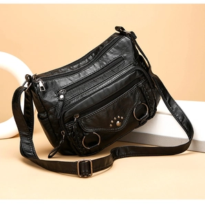 Detail view of black multi-pocket crossbody bag with cat-paw rivets and metal ring decor