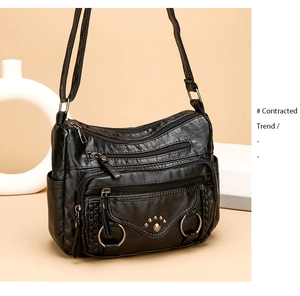 Detail of black multi-pocket crossbody bag with woven leather and rivet paw design