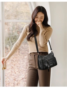 Adjustable strap detail on a black multi-zipper leather crossbody shoulder bag