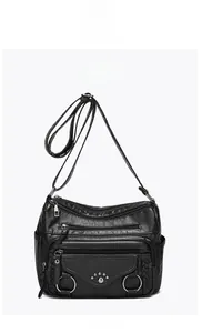 Front view of black multi-pocket crossbody bag with zipper layers and woven ring detail
