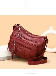 Macro shot of burgundy multi-pocket crossbody bag with woven details and smooth zippers