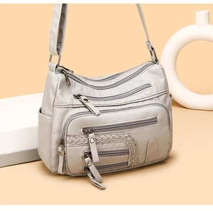 Detail view of light grey woven multi-pocket shoulder bag on beige geometric background