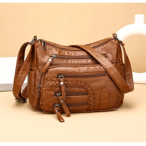 Detailed view of brown multi-zipper leather shoulder bag with woven side accents