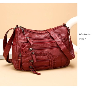Detail of dark red soft leather shoulder bag featuring multi-zipper layers and woven accents