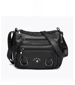 Front detail of black leather crossbody bag with multiple zip pockets and woven texture