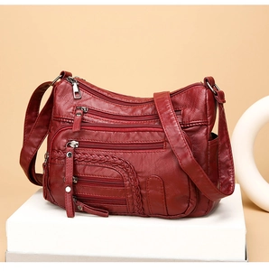 Detailed view of dark red multi-pocket shoulder bag with woven accents and silver zippers