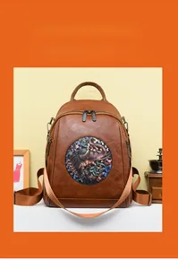 Detail view of dark brown leather backpack showing rich pebble texture and elephant patch
