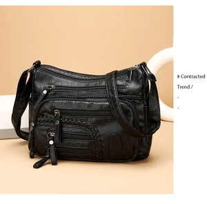 Close-up of black woven leather shoulder bag showing multiple zipper compartments and texture