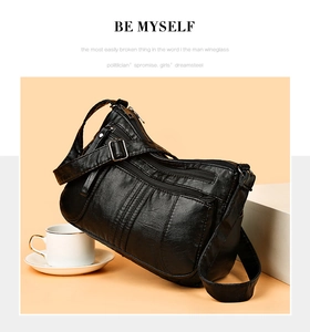 Detail of black soft leather crossbody bag featuring multiple zipper pockets and adjustable strap