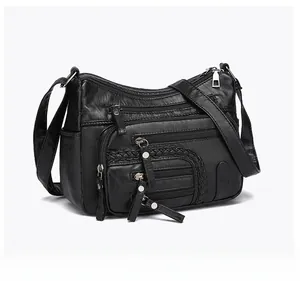 Detail of black multi-zipper crossbody bag with woven texture and adjustable strap
