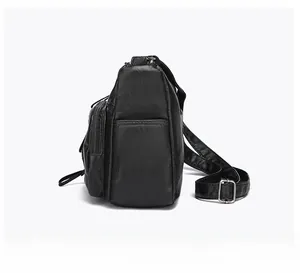 Side view of black pebble leather shoulder bag with side zipper pocket and strap