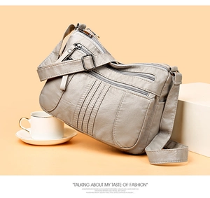 Detail of light gray soft leather shoulder bag with multiple functional zipper pockets