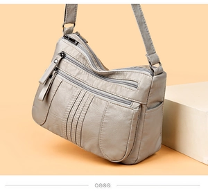 Detail view of grey faux leather crossbody bag with multiple zippers and pebble texture