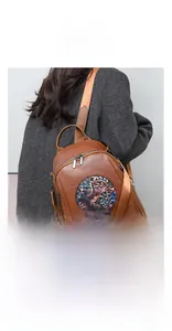 Rear view of brown leather backpack featuring a unique round artistic elephant embroidery