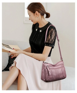 Asian model wearing a dusty pink multi-pocket soft leather shoulder bag in indoor setting