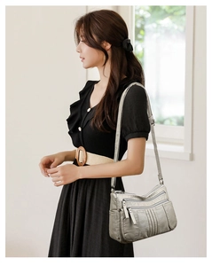 Detail of silver-grey multi-pocket shoulder bag with sleek metallic zippers and soft leather