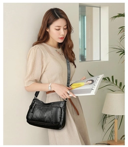 Detail of multi-pocket black soft leather shoulder bag with smooth zippers for women