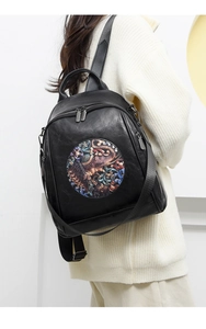Detail of black leather-textured backpack featuring embroidered elephant and floral pattern